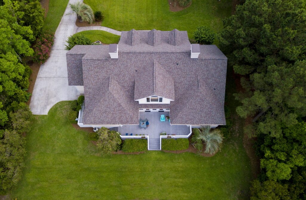 Aerial view of large home with new roof on beautiful property.