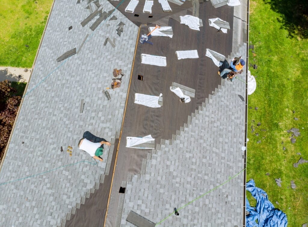 roofer working on replacement asphalt shingle roof construction